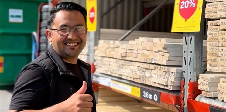 Employee of Byggmax showing thumbs up infront of storage.